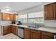 Galley kitchen featuring wood cabinets, stainless steel appliances, and a bright window overlooking the backyard at 1612 Suffolk Dr, Clearwater, FL 33756