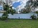 Backyard features a new white fence, mature trees and tropical foilage at 16240 Lake Palm Dr, Lutz, FL 33549