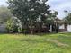 View of home featuring mature landscaping and brick accents with red shutters at 16240 Lake Palm Dr, Lutz, FL 33549