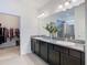 Elegant bathroom with double vanity, granite countertops, and large mirror, leading to walk-in closet at 17749 Garsalaso Cir, Brooksville, FL 34604