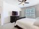 Bright main bedroom featuring a dark wood bed frame, a ceiling fan, and large windows at 17749 Garsalaso Cir, Brooksville, FL 34604