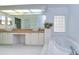 Spacious bathroom with tub, glass block window, and double sink vanity with tile countertop at 18828 Rue Loire, Lutz, FL 33558