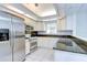 Well-lit kitchen featuring white cabinets, stainless steel appliances, and granite countertops at 18828 Rue Loire, Lutz, FL 33558