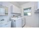 Well-lit laundry room features white appliances, cabinets, sink, and a window overlooking the outdoors at 18828 Rue Loire, Lutz, FL 33558