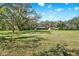 Scenic view of the expansive backyard featuring a covered patio and multiple storage sheds on an open lot at 2690 E Lake Trl, Tarpon Springs, FL 34688