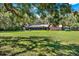 Expansive backyard featuring a covered patio, open lawn, and multiple storage sheds at 2690 E Lake Trl, Tarpon Springs, FL 34688