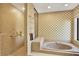 Bathroom featuring a sunken jacuzzi tub, neutral tile, and a glass enclosed shower at 2690 E Lake Trl, Tarpon Springs, FL 34688