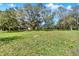 Spacious, grassy front yard with mature trees and a view of the house at 2690 E Lake Trl, Tarpon Springs, FL 34688