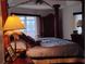 Elegant main bedroom featuring a four-poster bed, decorative lighting, and neutral tones creating a luxurious space at 28 Sportsman Pl, Rotonda West, FL 33947
