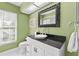 Stylish bathroom with green walls, black granite counters, and a decorative mirror at 2886 Armadillo Dr, Palm Harbor, FL 34683