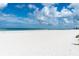 Expansive beach view with white sand under a cloudy blue sky at 3111 Pass A Grille Way # 213, St Pete Beach, FL 33706