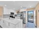Bright kitchen featuring stainless steel appliances, quartz countertops, and a door leading to a small balcony at 3111 Pass A Grille Way # 213, St Pete Beach, FL 33706