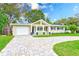 Charming single-story home featuring a well-manicured lawn and brick driveway at 316 Barbara Cir, Belleair, FL 33756