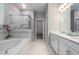 Bathroom features a bathtub, shower with glass door, double sink vanity, and tile flooring at 34303 Radley Way, Wesley Chapel, FL 33545