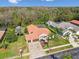 Aerial view shows home with brick driveway, screened in lanai and surrounding greenery at 3819 Brooksworth Ave, Tarpon Springs, FL 34688