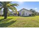 View of home's backyard with screened-in lanai, mature landscaping, and sunny skies at 3819 Brooksworth Ave, Tarpon Springs, FL 34688