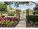 Walking path through wrought iron gate with brick pillars and lush landscaping near a pond at 3819 Brooksworth Ave, Tarpon Springs, FL 34688