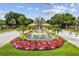 Community entrance featuring colorful flowers, lush green grass, and mature trees on a sunny day at 3819 Brooksworth Ave, Tarpon Springs, FL 34688