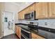 Kitchen featuring stainless steel appliances, granite countertops, wood cabinets and a door to the laundry room at 3819 Brooksworth Ave, Tarpon Springs, FL 34688