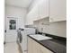 Well-equipped laundry room featuring a sink, storage cabinets, and a modern washer and dryer at 3819 Brooksworth Ave, Tarpon Springs, FL 34688