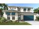 Stunning two-story home featuring a blue garage door, awnings, lush landscaping, and a paver driveway at 3821 109Th Street East, Palmetto, FL 34221