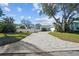 View of the property showing the expansive side yard and brick driveway with mature trees at 436 3Rd N Ave, Tierra Verde, FL 33715