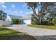 Wide, elegant brick driveway leading to an attached two-car garage with a privacy fence and mature trees at 436 3Rd N Ave, Tierra Verde, FL 33715