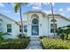 Charming home exterior with lush landscaping, a striking blue front door, and manicured front yard at 436 3Rd N Ave, Tierra Verde, FL 33715