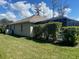 View of the backyard with a screened in patio, well-maintained lawn, and manicured hedge row at 514 Cedar Woods Dr, Oldsmar, FL 34677