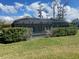 View of the backyard with a screened in patio, well-maintained lawn, and manicured hedge row at 514 Cedar Woods Dr, Oldsmar, FL 34677