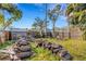 This grassy backyard features a wood pile, a privacy fence, and plenty of shade at 80 Squire Ct, Dunedin, FL 34698