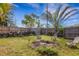 This grassy backyard features a burn pile, a privacy fence, and plenty of shade at 80 Squire Ct, Dunedin, FL 34698
