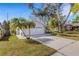 Charming home with a well-maintained lawn, mature trees, and a driveway leading to a garage at 80 Squire Ct, Dunedin, FL 34698