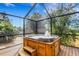 Hot tub with a fountain feature in a screened enclosure, surrounded by landscaping and a view of the sky at 80 Squire Ct, Dunedin, FL 34698