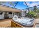 Relaxing hot tub with waterfall feature on a screened-in patio next to the house with white french doors at 80 Squire Ct, Dunedin, FL 34698