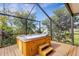 Outdoor hot tub with waterfall feature, set within a screened enclosure, surrounded by lush greenery at 80 Squire Ct, Dunedin, FL 34698