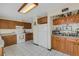 Bright kitchen featuring white appliances and wood cabinetry, offering ample storage and counter space at 80 Squire Ct, Dunedin, FL 34698