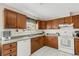 Well-lit kitchen featuring wood cabinets, and white appliances, including a dishwasher at 80 Squire Ct, Dunedin, FL 34698