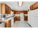 Kitchen with wood cabinets, white appliances, and tile flooring providing a functional space at 80 Squire Ct, Dunedin, FL 34698