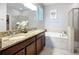 Bright bathroom featuring a dual-sink vanity with granite countertop and a separate tub with tiled surround at 924 Peregrine Hill Pl, Ruskin, FL 33570