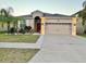 Charming single-story home featuring a well-manicured lawn, a two-car garage, and tropical landscaping at 924 Peregrine Hill Pl, Ruskin, FL 33570