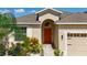 A detailed image of a front door with vibrant landscaping, a brick-paved path, and a decorative arched entryway at 924 Peregrine Hill Pl, Ruskin, FL 33570