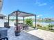 A shady outdoor dining area, with a black pergola, string lights, and view of the water at 924 Peregrine Hill Pl, Ruskin, FL 33570