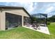 Spacious backyard with a screened-in patio, outdoor seating, and lush green lawn for recreation and relaxation at 10428 Arbor Groves Pl, Riverview, FL 33578