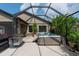 Relaxing screened-in patio featuring a luxurious hot tub, stainless steel grill, and comfortable seating area at 10428 Arbor Groves Pl, Riverview, FL 33578