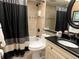 Modern bathroom featuring a black shower curtain, black hardware, and decorative patterned tile flooring at 1235 S Highland Ave # 1-204, Clearwater, FL 33756