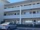 Three-story building exterior featuring white decorative balconies and neutral stucco with well-maintained shrubbery at the base at 1235 S Highland Ave # 1-204, Clearwater, FL 33756