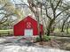 Exterior of red barn with white trim, framed by mature trees at 13607 Mcintosh Rd, Thonotosassa, FL 33592