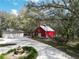 Large property featuring a red barn, garage, fountain, and mature trees at 13607 Mcintosh Rd, Thonotosassa, FL 33592