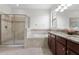 A bathroom featuring a glass shower, soaking tub, brown cabinets, and dual sinks at 19476 Paddock View Dr, Tampa, FL 33647